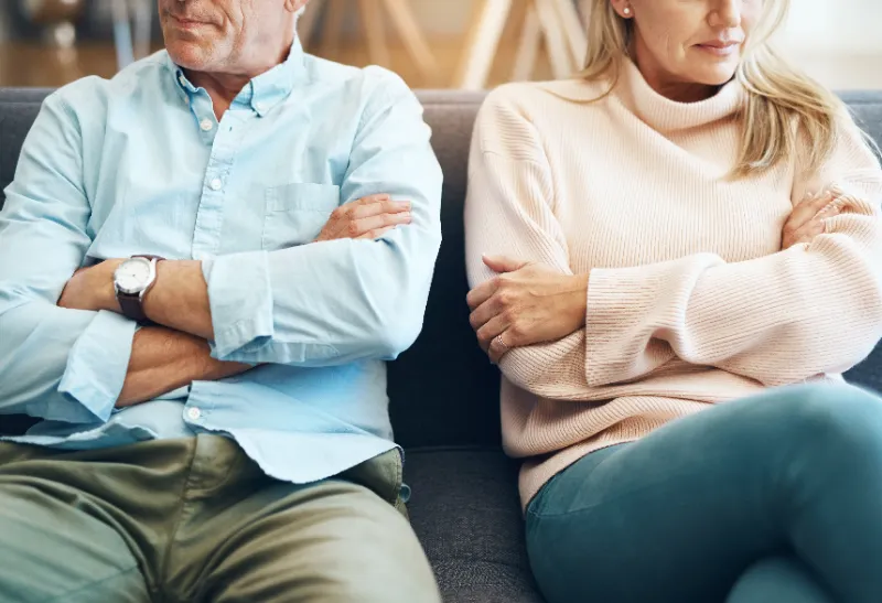 Colorado couple sitting apart on a couch, symbolizing emotional distance during divorce.