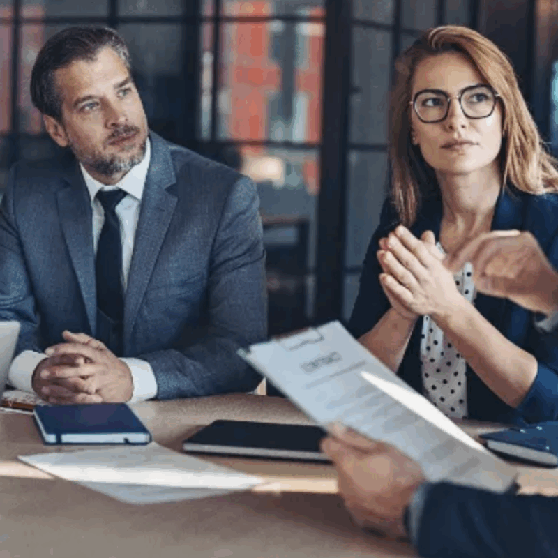 Professional couple meeting with a mediator in an office, discussing divorce settlement options in Colorado.