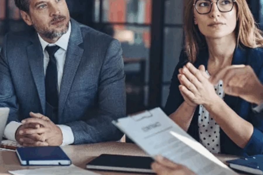 Professional couple meeting with a mediator in an office, discussing divorce settlement options in Colorado.