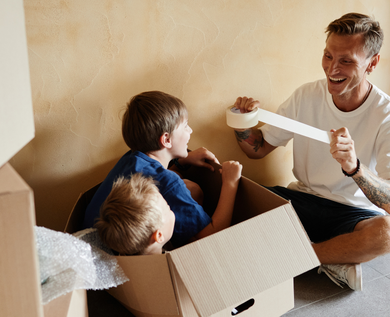 Father packing moving boxes with his children during a family relocation